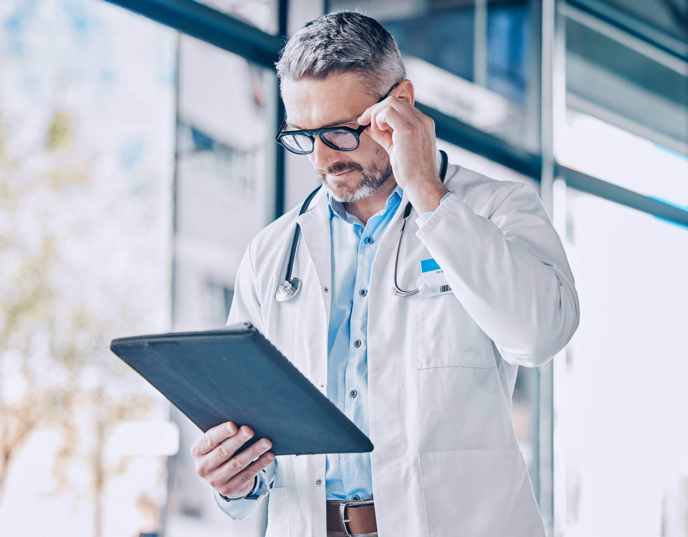 Mature doctor man, reading tablet and thinking with report, medical information or paperwork for in.